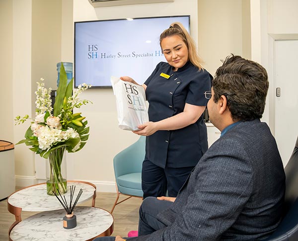 Receptionist presents a bag to a patient in a waiting room