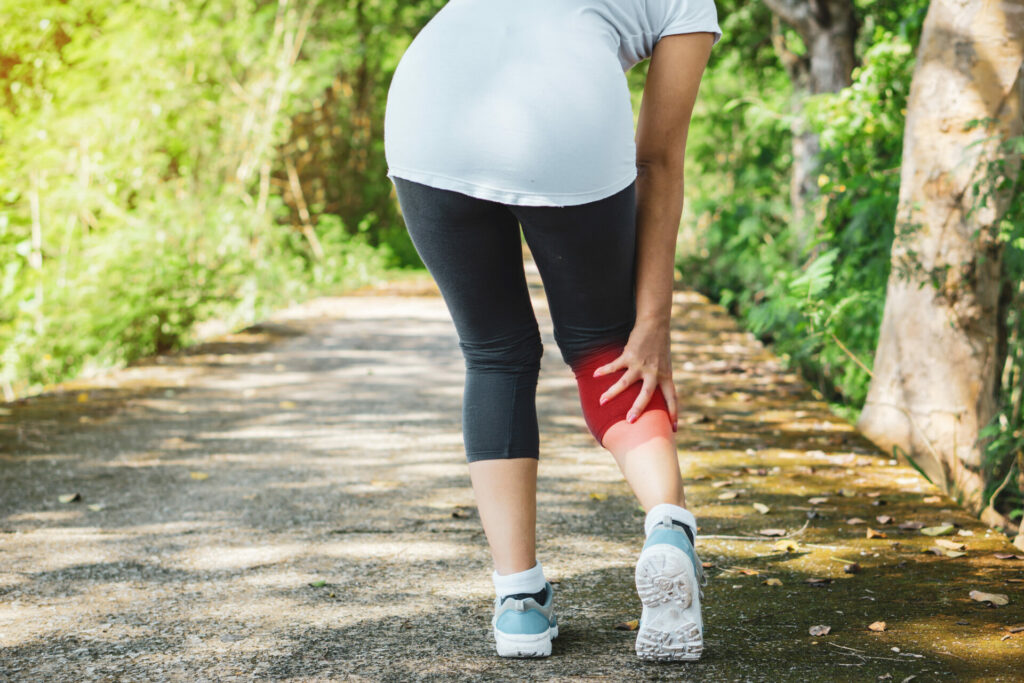 female jogger with leg pain while out running in the park