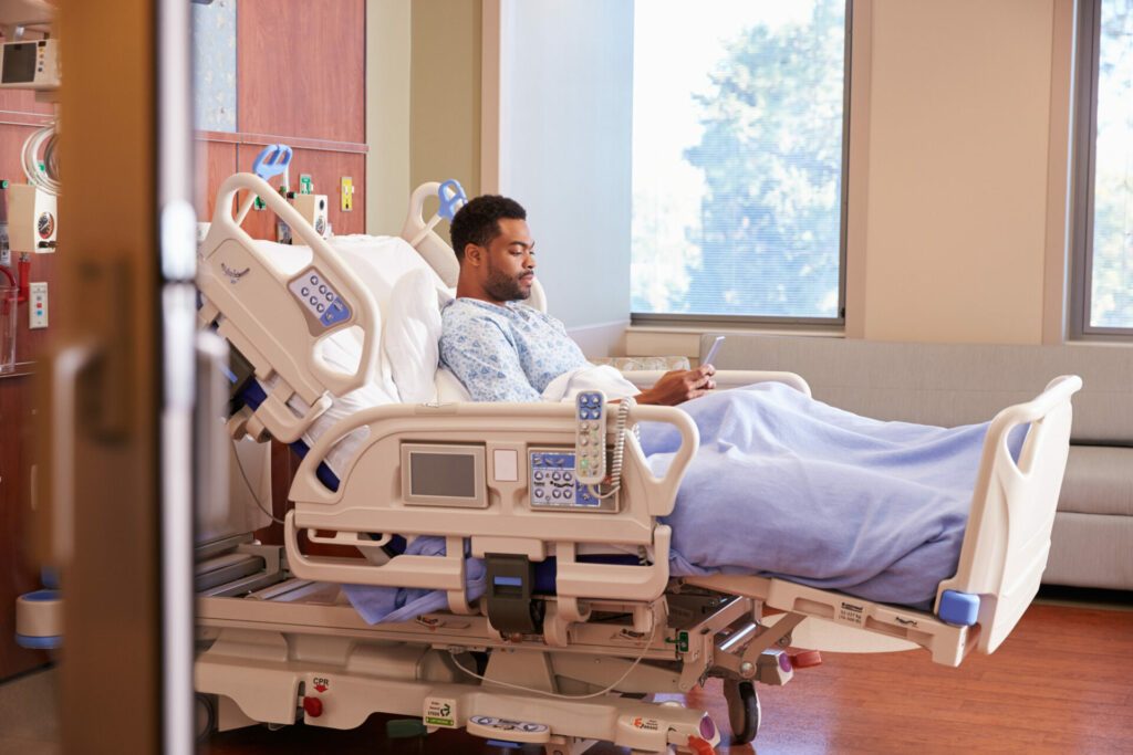 patient in bed looking at his cellphone