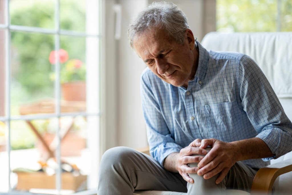 sitting man clutches knee is pain