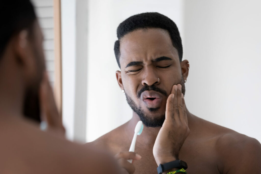 man trying to brush his teeth with jaw pain